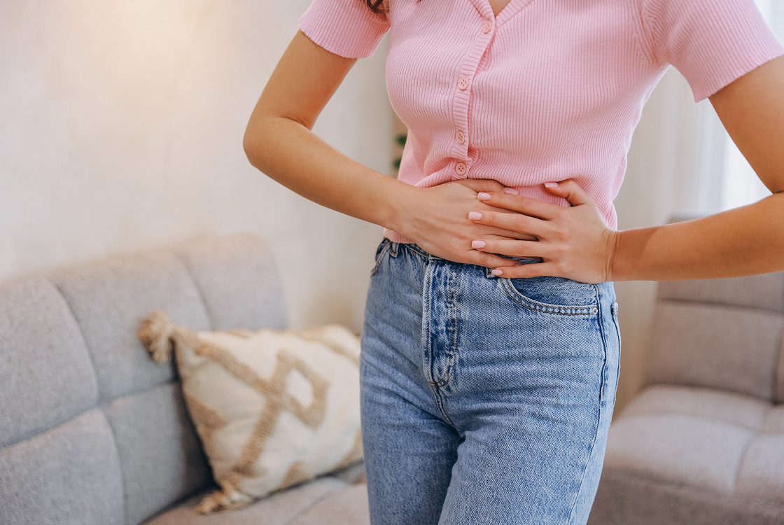 Woman experiencing abdominal pain indoors